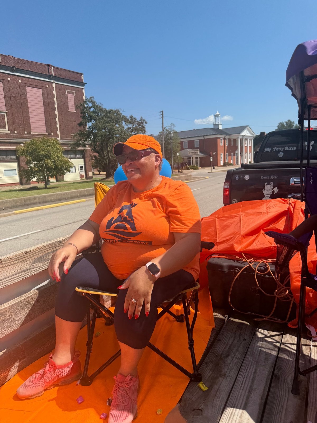 Artie in orange campaign shirt and cap smiling while sitting in the back of a parade truck during the Cairo Heritage Blues Fest