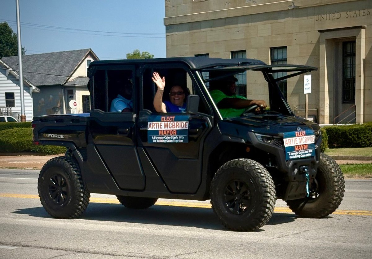 Black pickup truck towing the Artie McBride for Mayor trailer with another black utility vehicle alongside at the parade