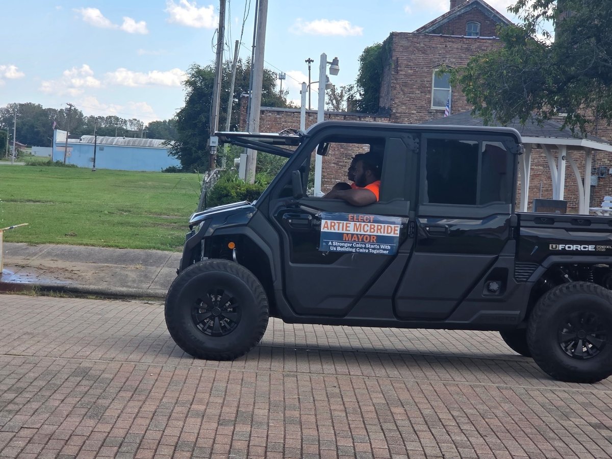 Black utility vehicle with ELECT ARTIE MCBRIDE MAYOR campaign sign parked on brick pavement during the parade